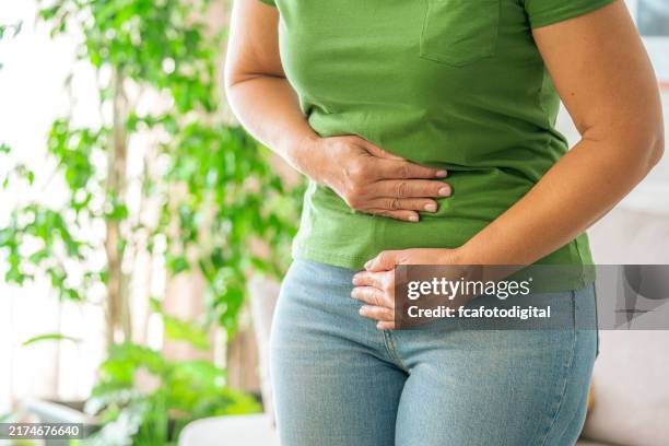 Woman touching her stomach experiencing abdominal pain at home